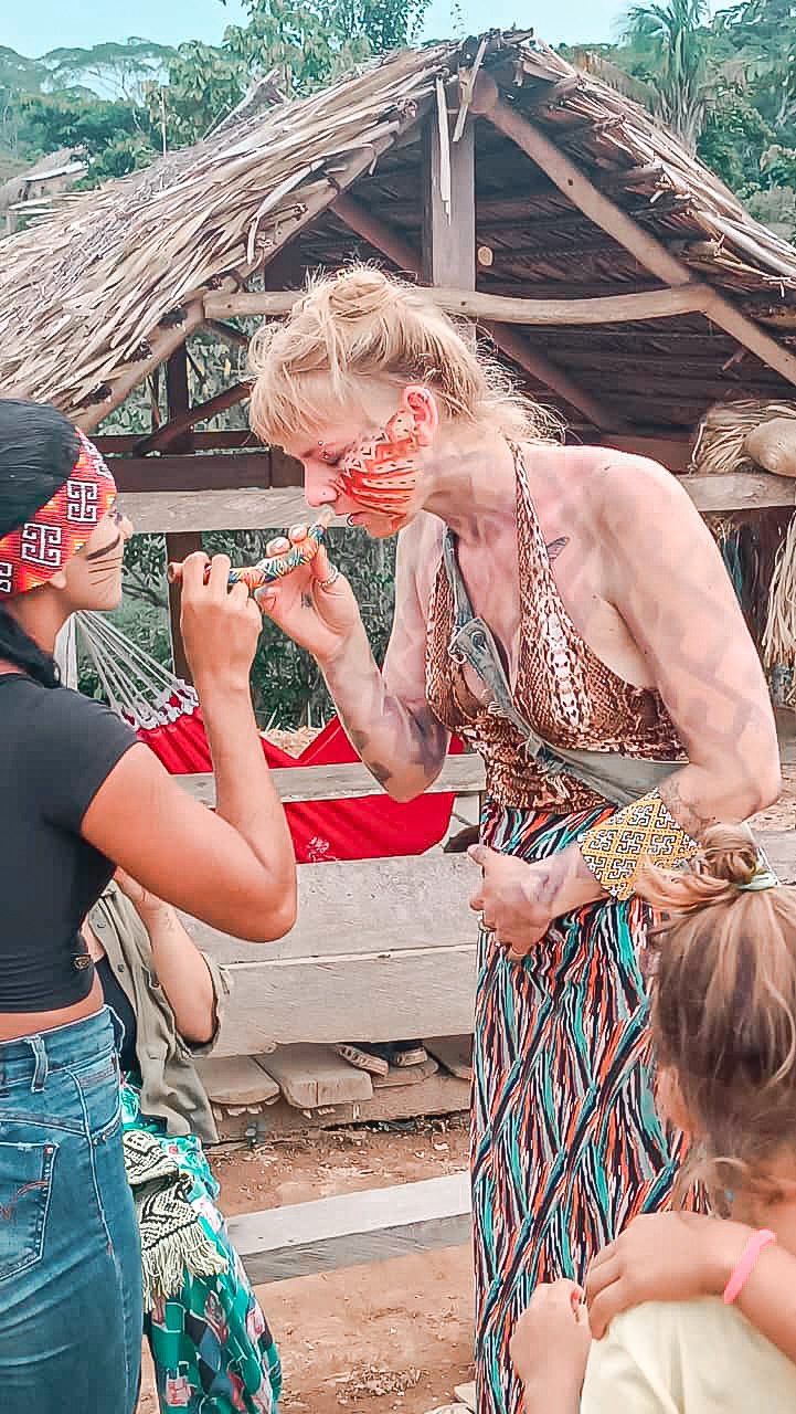 Traveler receiving traditional rapé ceremony from an indigenous woman in the Amazon rainforest of Brazil