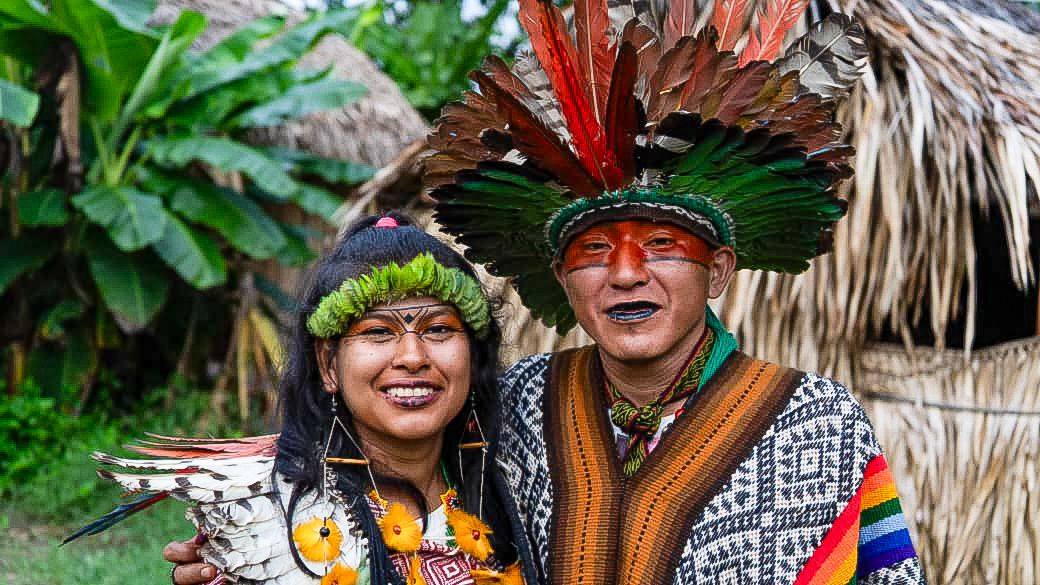 Amazon indigenous Huni Kuin couple in traditional clothing standing in the rainforest near their community in Brazil
